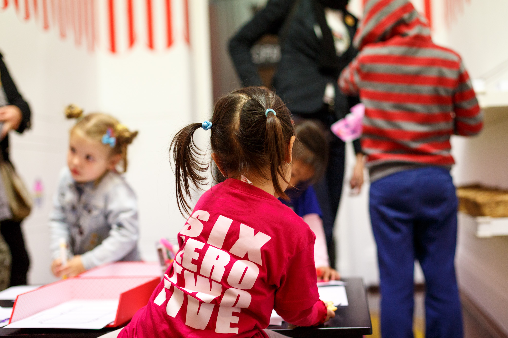 A small girl wearing a pink SIX ZERO TWO FIVE shirt by exhibiting street-inspired artist Trevor Bly.